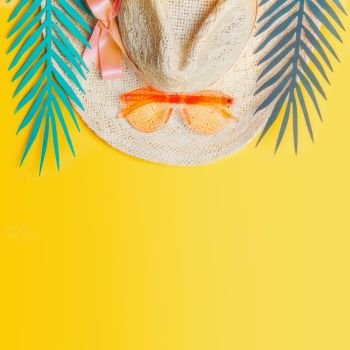 Straw hat with orange sunglasses and tropical leaves on yellow background, top view. Summer holiday concept. Tropical vacation . Flat lay. Copy space