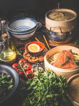 Asian cuisine. Various ingredients, utensils and tools on kitchen table.  Authentic asian food cooking preparation with salmon,seasoning, spices, bowls and chopsticks