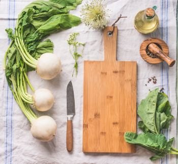 Raw young turnip  with greens on light kitchen table with empty cutting board and knife, top view. Healthy vegetarian clean eating and cooking concept. Copy space