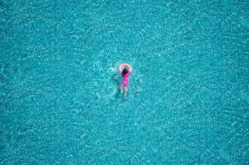 Top view of girl swimming in the pool.