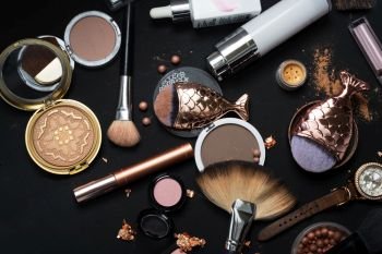 Set of bronze powder with makeup brushes on black background