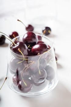 Sweet cherries in cherry  glass bowl around white. close up