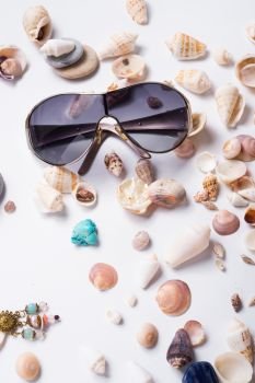 fashion sun eyeglasses around marine shells at white background