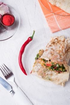 international vegetarian  shawarma sandwich roll with chili and spices. served at white table. arabian and caucaisian cuisine. Healthy fast food. flat lay