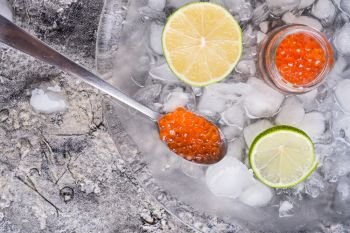  fresh red  salmon caviar with lime slices around ice. Protein luxury delicacy  healthy food