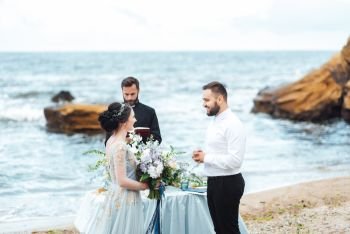 wedding couple on the ocean with a priest
