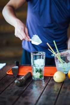 Barman prepares fruit alcohol cocktail based on lime, mint, orange, soda and alcohol