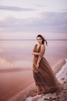 girl on the shore of a pink salt lake at sunset