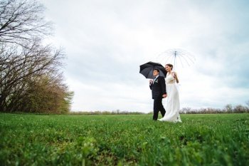 bride and groom on a rainy wedding day walking under an umbrella