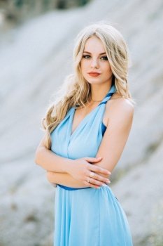 blonde girl in a light blue dress  in a gray granite quarry