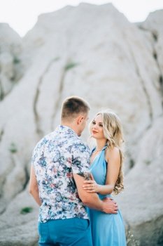 blonde girl in a light blue dress and a guy in a light shorts and short shert in a granite quarry