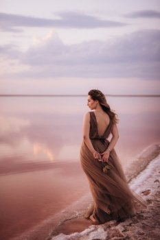girl on the shore of a pink salt lake at sunset