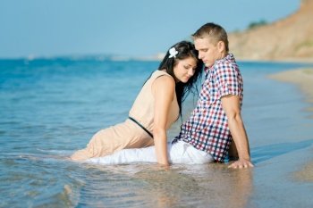 a guy and a girl walk along the seashore, swim in the water