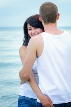 guy and a girl in jeans and white t-shirts on the seashore