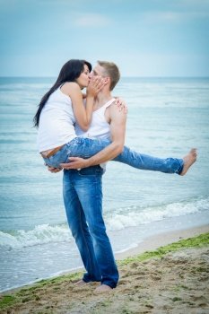 guy and a girl in jeans and white t-shirts on the seashore