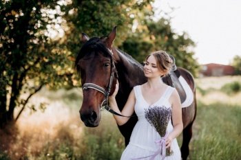 girl in a white sundress on a walk with brown horses in the village