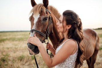 bride in a white dress next to a brown horse in the village