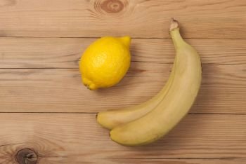 Lemon and bananas on a wooden background. View from above .. Lemon and bananas on a wooden background. 
