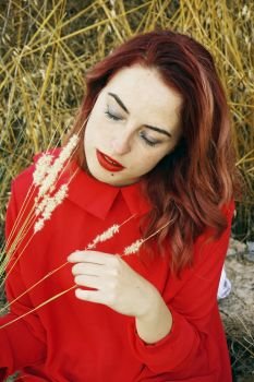 Young and beautiful redhead woman enjoying nature in autumn                               