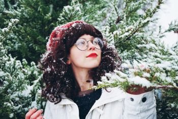 Young and pretty woman enjoying a snowy winter day surrounded by trees                               
