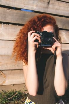 Young redhead photographer woman enjoying her passion outdoors