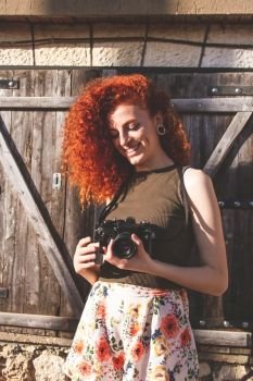 Young redhead photographer woman enjoying her passion outdoors