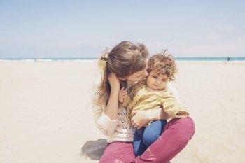 Young mom playing at the beach with her child