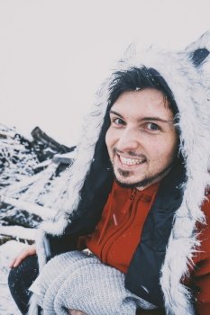 Young man enjoying a snowy day wearing a fur hat and a red hoodie