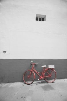 Red bicycle on a white wall background. black and red and white photo