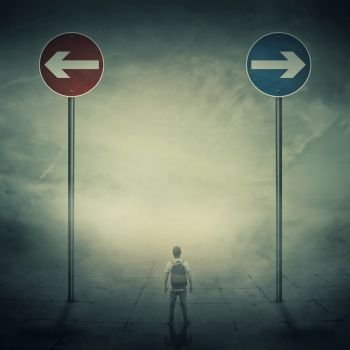 Surrealistic image as a man, with a bag in his back, stand in a foggy street in front of two huge road signs that show the left and right directions. Strategic journey, way of life and intuition concept.