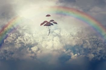 Imaginary view with a young boy flying above clouds holding a lot of umbrellas. Life journey below a rainbow in the sky.