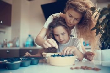 mother and daughter prepare a pie / home mom and daughter in kitchen bake a blueberry pie, the concept of  family home cosiness