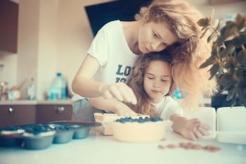 mother and daughter prepare a pie / home mom and daughter in kitchen bake a blueberry pie, the concept of  family home cosiness