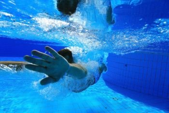 man dives into the pool underwater photo