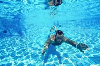 man dives into the pool underwater photo