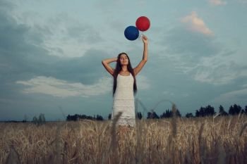 Dream, happiness - young girl in a field with flying balloons