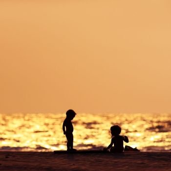 silhouettes of two young children beach sunset