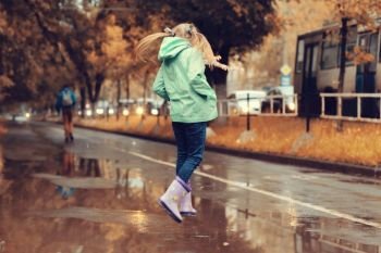 girl jumping in the puddles in the autumn rain