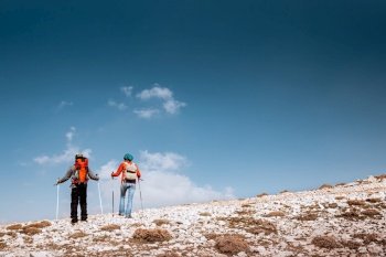 Couple enjoying hiking in wintertime. The desire for heights and extremes, what inspired these brave tourists to the highest mountains.. Active Couple Walking with Sticks in the Mountains