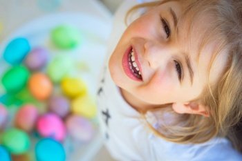 Portrait of a cute little baby boy looking up with happiness and hope. Playing with colorful eggs. Eggs hunting. Happy holidays.. Happy Children on Easter Celebration