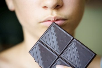 Closeup of crop unrecognizable teenage girl holding chocolate bar at home. Unrecognizable teenage girl holding chocolate bar at home