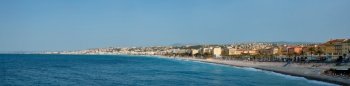 Picturesque scenic panorama of Mediterranean sea coast in Nice, France. Mediterranean Sea waves surging on the coast, people are relaxing on the beach. Nice, France. Picturesque view of Nice, France