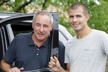 smiling dad and son outside black car