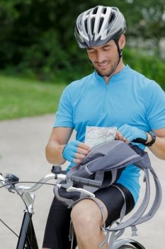 male recreational cyclist putting map inside bag