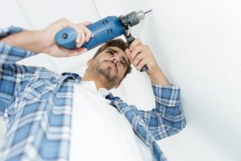 male builder drilling holes in wall at construction site
