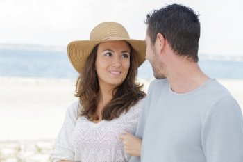 couple walking arm in arm by the beach