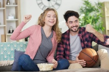 young couple watching basketball match on tv