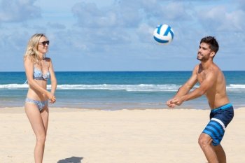 young couple playing volley on the beach