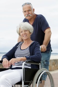 senior couple with wheelchair on a walk