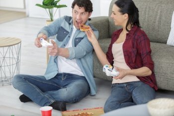 woman feeding pizza to man playing computer game